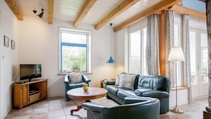 Un salon avec un téléviseur, un canapé en cuir et une table basse.