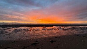 A beach with a sunset, wet sand, and footprints. - Pet-friendly home in Callanstoog near beach (Callantsoog)