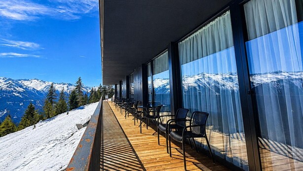 Ein Balkon mit Stühlen und Blick auf schneebedeckte Berge.