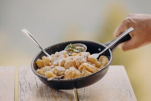Un bol de pâtes avec une cuillère, sur une table en bois.