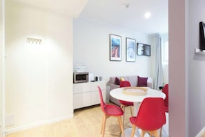 A modern living room with a dining area, a sofa, a TV mounted on the wall, and a microwave on the counter. - Charming Studio 4P - Milano Centrale (Milano)