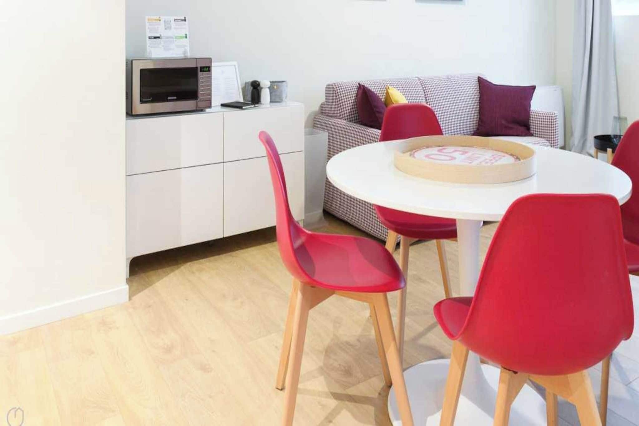 Eine moderne Küche mit Mikrowelle, einem weißen Schrank und einem karierten Sofa.