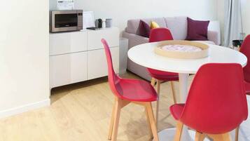 Eine moderne Küche mit Mikrowelle, einem weißen Schrank und einem karierten Sofa.