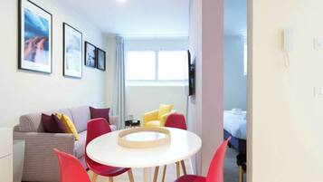 Ein modernes Hotelzimmer mit einer karierten Couch, roten Stühlen, einem runden Tisch und gerahmten Bildern an der Wand.