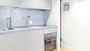 Eine moderne Küche mit weißen Schränken, einer Edelstahl-Spüle und einem Backofen.