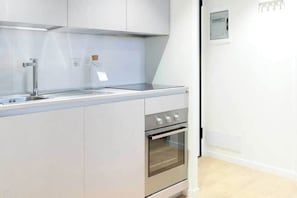 A modern kitchen with white cabinetry, a stainless steel sink, and an oven. - Charming Studio 4P - Milano Centrale (Milano)