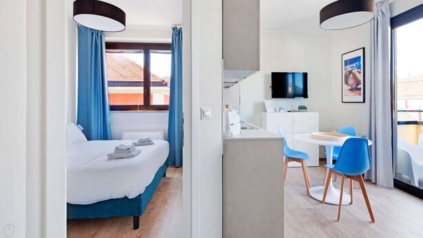 Ein Hotelzimmer mit Bett, Schreibtisch, Stuhl, Fernseher und Blick ins Freie.