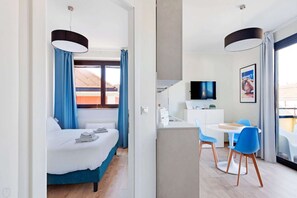 Une chambre d’hôtel équipée d’un lit, d’un bureau, d’une chaise, d’une télévision et offrant une vue sur l’extérieur.