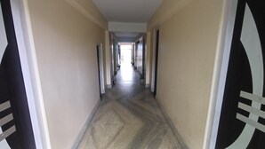 A hallway with a herringbone floor pattern, beige walls, and black and white decorative panels. - A India Guest House (Mohanpur)