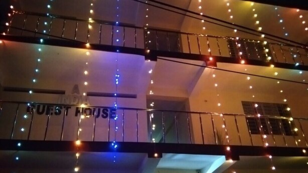 A multi-story building with balconies, a sign reading 'HOST HOUSE,' and string lights. - A India Guest House (Mohanpur)
