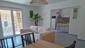 Un espacio habitable moderno con comedor, cocina y balcón amoblado.