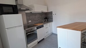 Una cocina moderna con armarios blancos, horno integrado, microondas y encimera de madera.