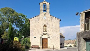 Una iglesia con un campanario, un reloj y una estatua sobre la entrada.
