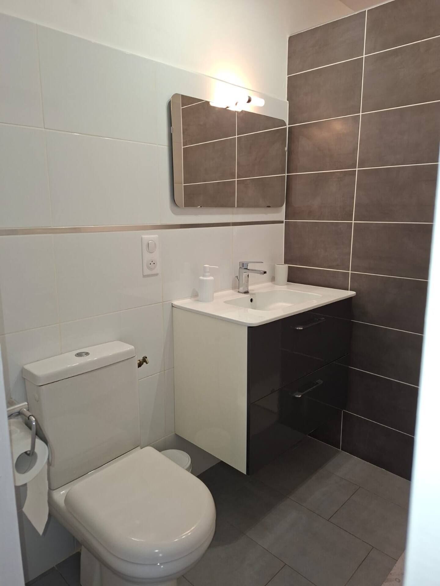 A small bathroom with a toilet, sink, and mirror.