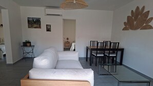 Una sala moderna con sofá, mesa de comedor, sillas y una mesa baja de vidrio.