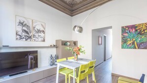 A modern living room with a flat-screen TV, yellow chairs, a dining table with a vase of flowers, and artwork on the walls. - Indipendenza (Bologna)