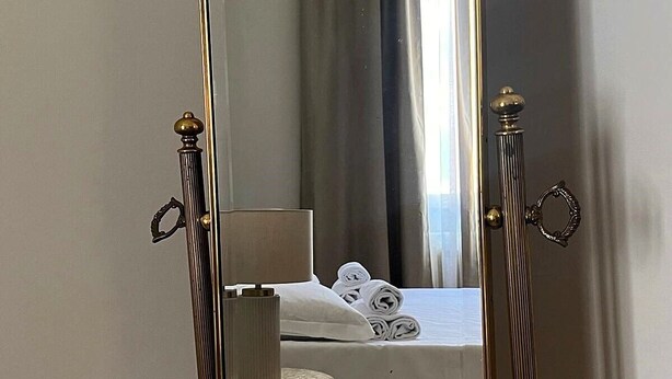 Ein Hotelzimmer mit einem Bett, einem kleinen runden Tisch, einer Lampe und einem Spiegel.