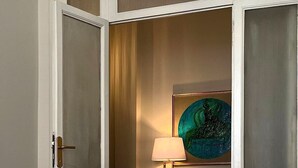 Ein Zimmer mit Glastisch, zwei Stühlen, einer Lampe und einer Wanddekoration.