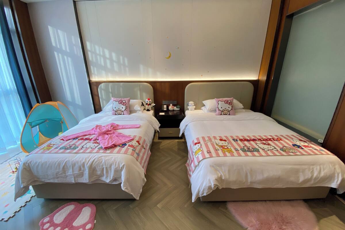 Habitación de hotel con dos camas, una mesita de noche, una ventana con cortinas y una alfombra rosa y esponjosa.