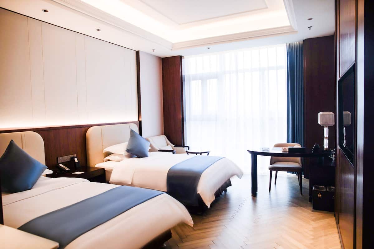 Una habitación de hotel con dos camas, un escritorio, una silla y un televisor.