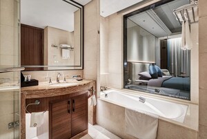 Un baño moderno con un espejo grande, una bañera y un tocador con lavabo.