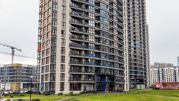Um edifício residencial alto com várias varandas, um telhado plano e um design arquitetônico moderno.