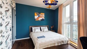 Quarto com cama, janela e vista para a cidade.