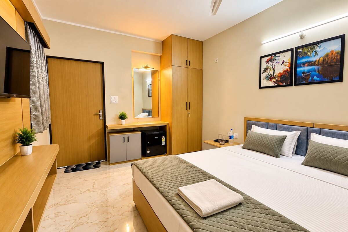 A hotel room with a bed, bedside table, TV, wardrobe, and artwork on the wall.