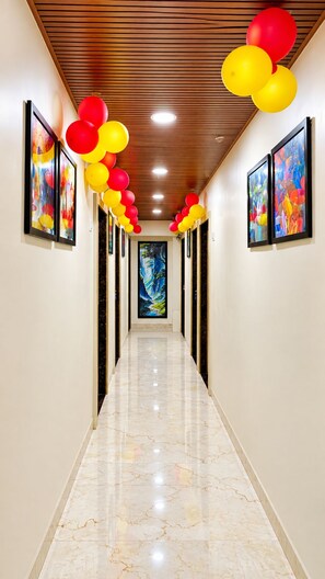 A corridor with a marble floor, wooden ceiling, and framed artwork on the walls. - The Valoria, Vijay Nagar, Indore (Indore)