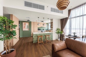 A modern kitchen with wooden cabinets, a green island, and bar stools. - Modern 1BR in Prime Business Bay | Sleeps 2 - StayShort (Business Bay)
