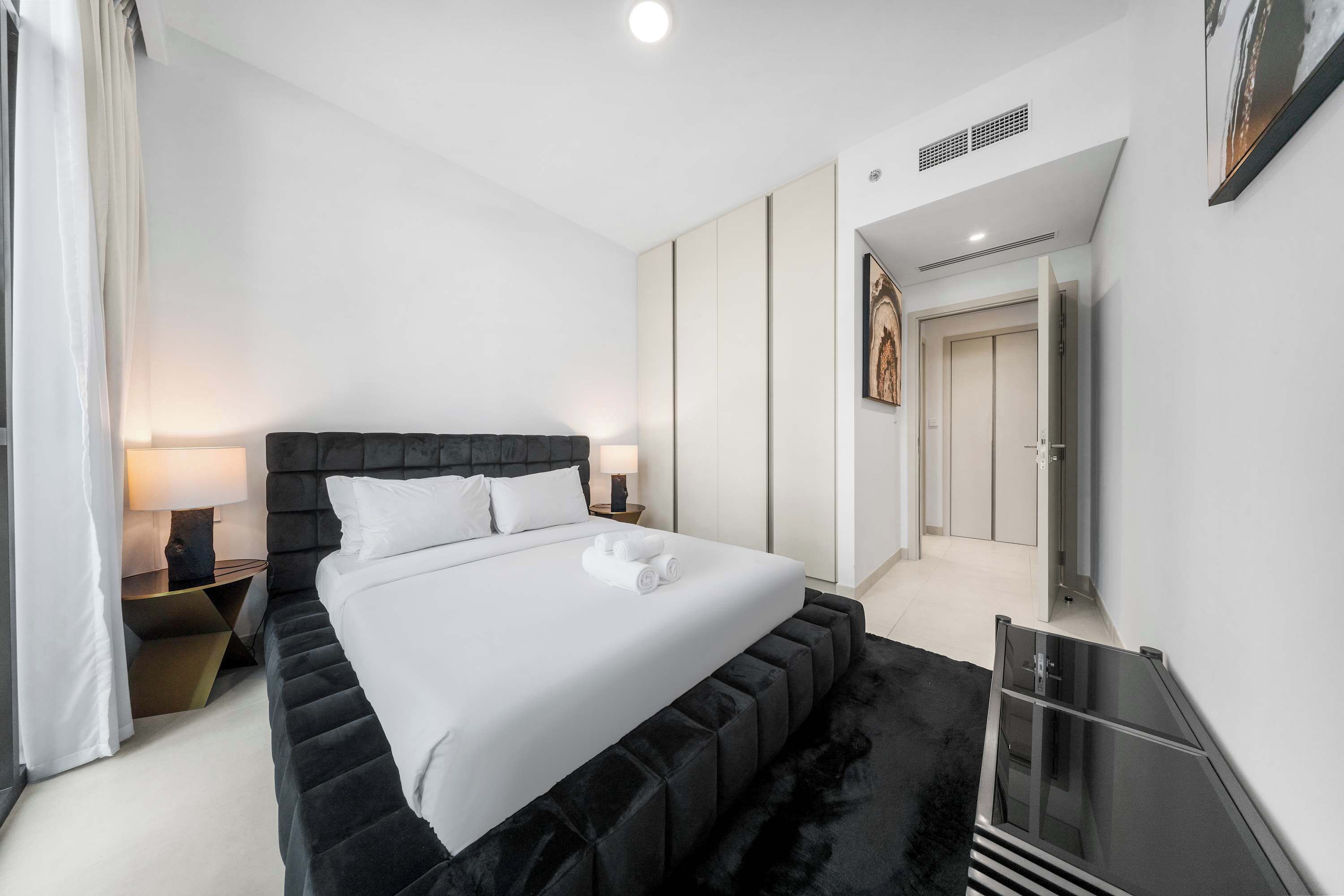 Une chambre d’hôtel moderne avec un grand lit, une table de chevet, une lampe et une armoire.