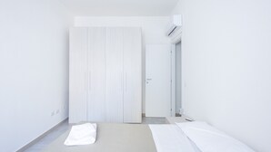Een minimalistische slaapkamer met een bed, een garderobe en een airconditioning.
