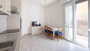Een moderne keuken met een ingebouwde kookplaat, een eethoek met een tafel en stoelen, en een schuifpui naar een buitenruimte.
