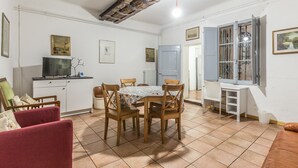 Una zona pranzo con tavolo e sedie, una TV su un mobile e una finestra con vista.