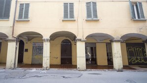 Un edificio con portali ad arco e una porta chiusa da persiana.