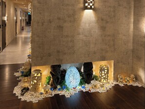 A hallway with a decorative wall feature, including a patterned wall light and a series of illuminated lanterns. - Hotel BaliBali Sendai (Sendai)