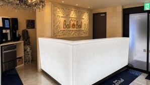 A hotel reception desk with a floral wall design, a chandelier, and a digital kiosk. - Hotel BaliBali Sendai (Sendai)