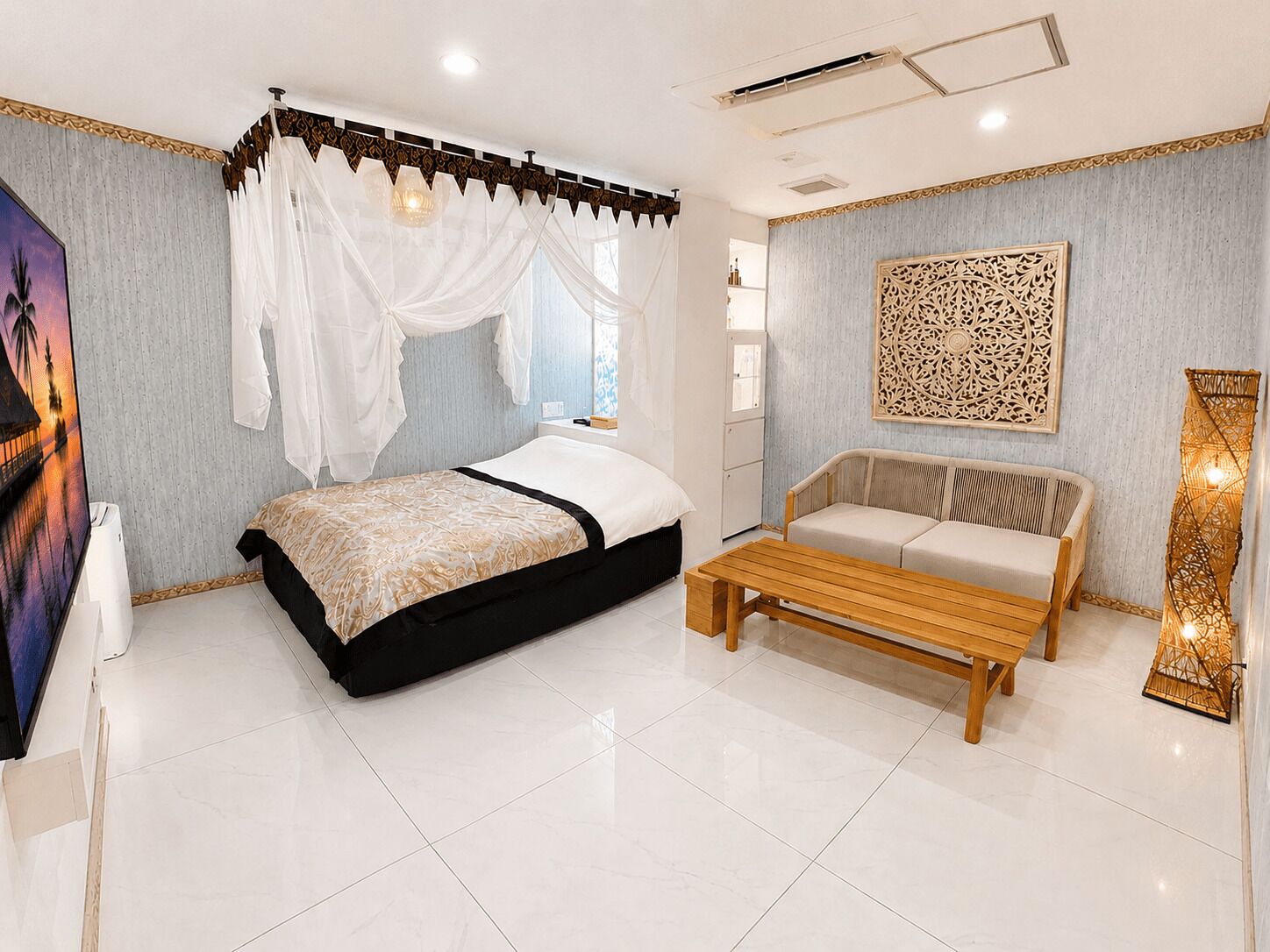 A bedroom with a bed, a sofa, a bedside table, and a decorative wall piece.