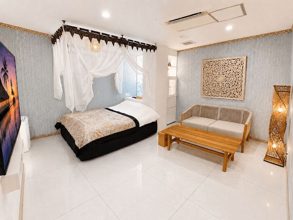 A bedroom with a bed, a sofa, a bedside table, and a decorative wall piece.