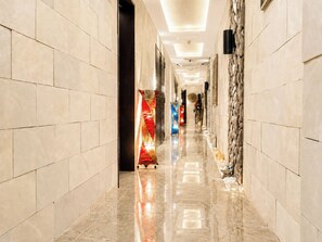 A hotel corridor with tiled walls, a polished floor, and a decorative light fixture. - Hotel BaliBali Sendai (Sendai)