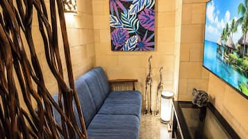Una habitación con un sofá azul, un cuadro colgado en la pared, un televisor y una escultura decorativa de un elefante.