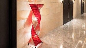 A hallway with a modern abstract sculpture, a marble floor, and a series of doors. - Hotel BaliBali Sendai (Sendai)