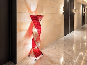 A hallway with a modern abstract sculpture, a marble floor, and a series of doors.