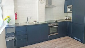 Una cucina moderna con lavello in acciaio inossidabile, forno integrato e orologio a parete.