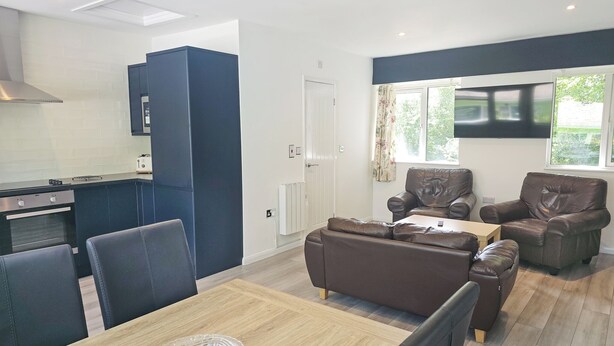Una cucina moderna con armadietti blu scuro, forno integrato e un'area pranzo con tavolo e sedie in legno.