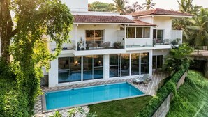 A two-story house with a swimming pool, balconies, and lush greenery. - Aroha Palms Luxury Apartments (Mandrem)