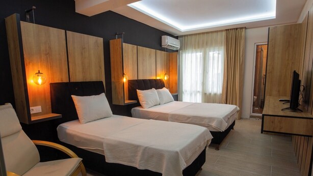 Habitación de hotel con dos camas, una silla, un escritorio y un televisor.