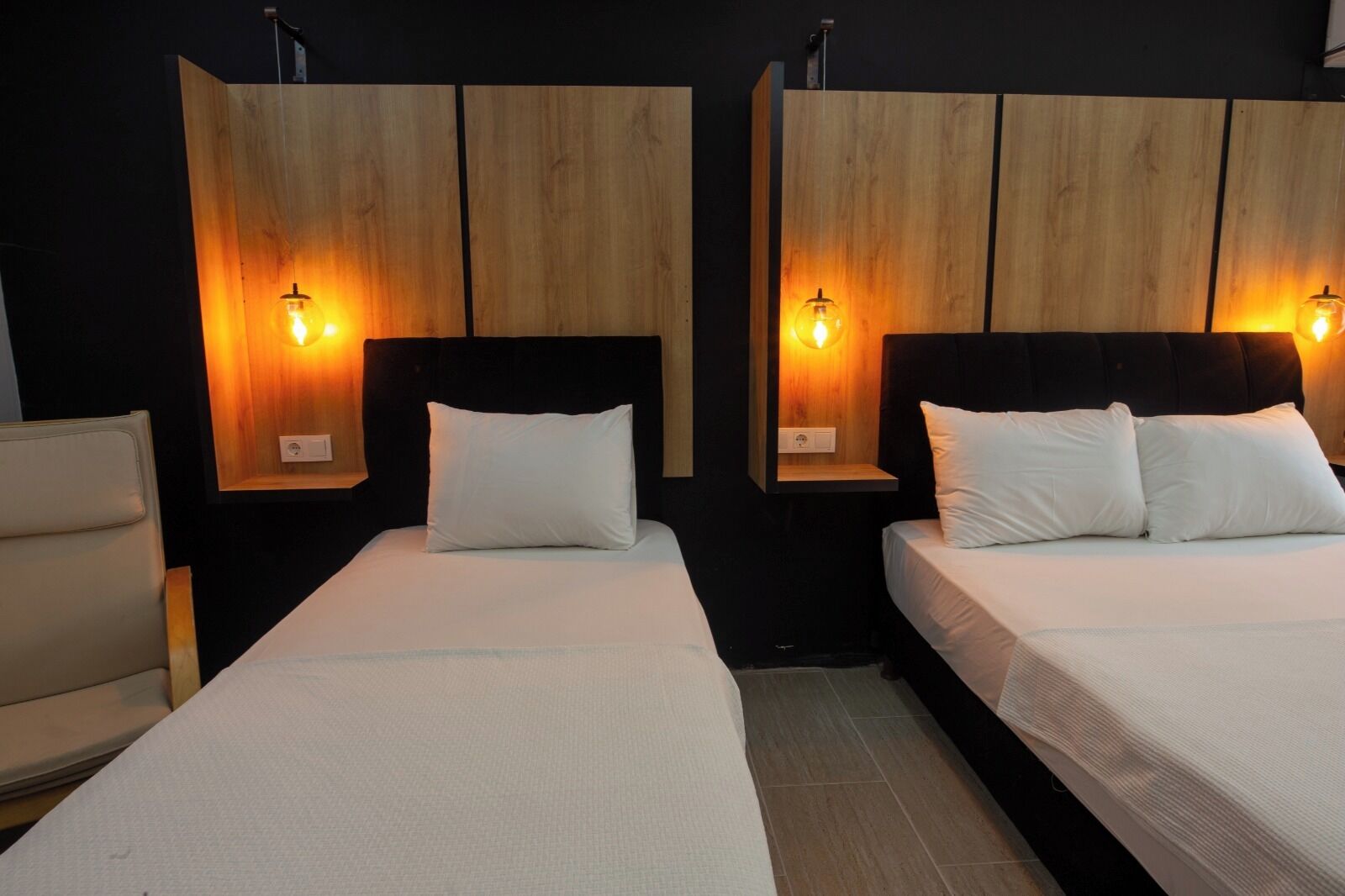 Habitación de hotel con dos camas, cada una con cabecero de madera y lámparas de noche.