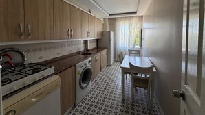 Una cocina compacta con estufa, lavadora y comedor con mesa y sillas.