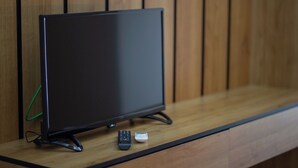 Un televisor sobre una superficie de madera, con un control remoto y un adaptador de corriente.